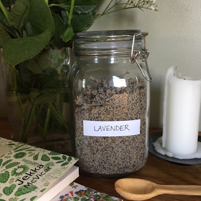 Jar of Dried Lavender next to wooden spoon and herbal books