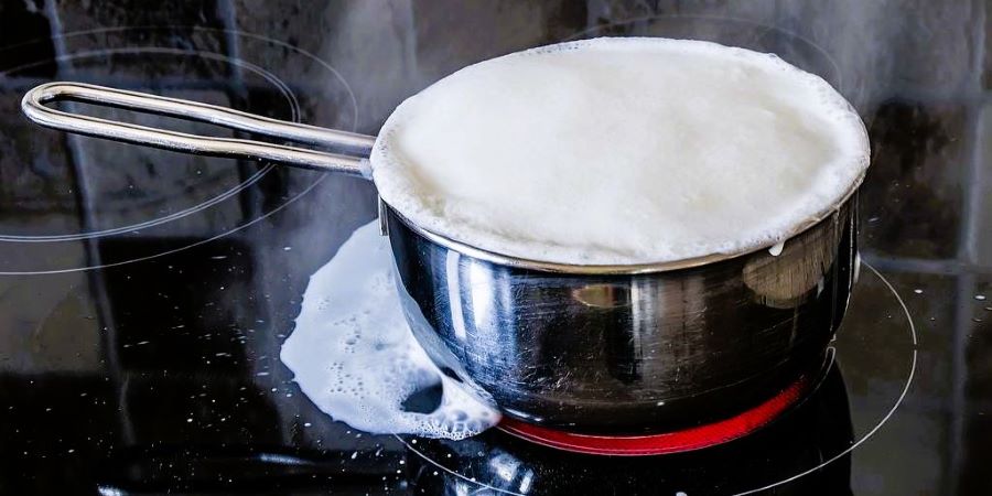 Leche derramándose de un cazo mientras se hierve.