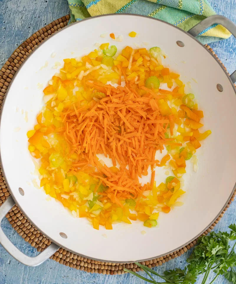 Carrots with sauteed vegetables in a large open dutch pot.