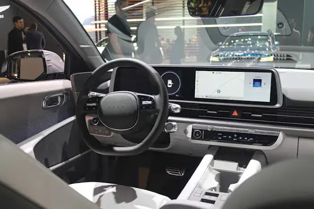 A dark gray steering wheel inside Hyundai Ioniq 6 car with two screens behind it.