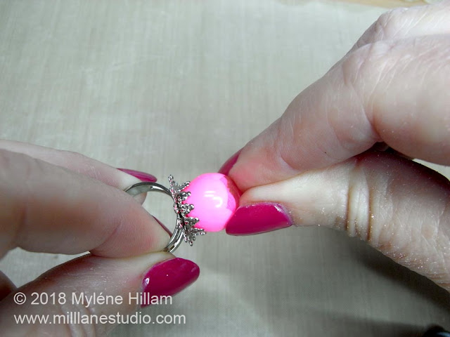 Pressing the bead firmly into the filigree ring base.