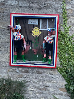 Flowerpot sculpture of 2 people in Union Jack shirts and hats.