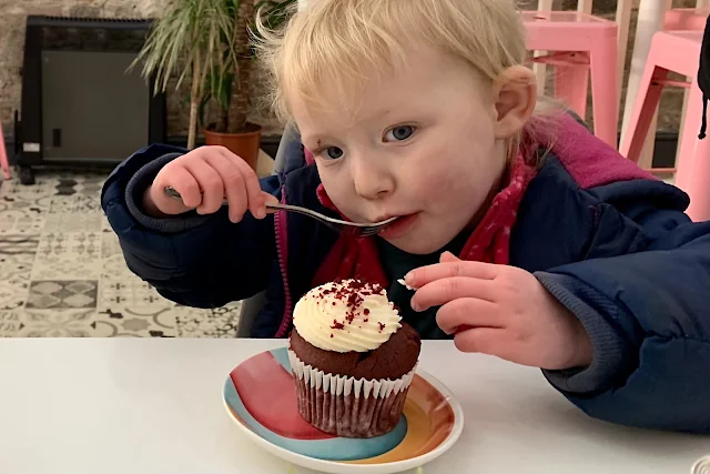 A toddler eating a red velvet cake and fully focussing on it