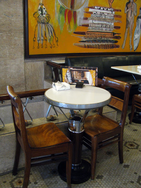 mesa redonda e duas cadeiras antigas do café Guarany