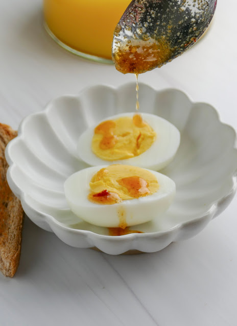 a spoon drizzling butter on hard boiled egg halves.