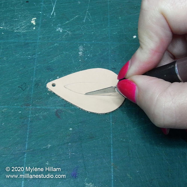 Cutting out the peep hole in the leather shape using a scalpel.