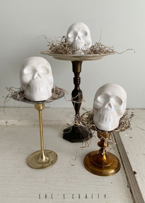 Ceramic Skulls sitting on display stands with spanish moss.