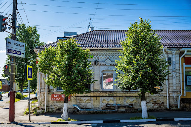 Одноэтажное старое здание за небольшими деревьями