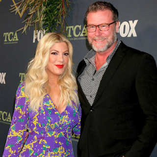 Tori Spelling and Dean McDermott smiling together at an event