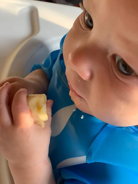 Close up of 6 month old baby feeding himself a banana