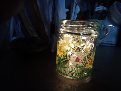 Photo of the daffodil painted jar filled with lit-up fairy lights, shining in the darkness