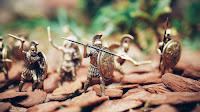 Close up photo of a set of little figurines of soldiers, possibly Greek or Roman, engaged in fighting