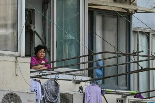 A resident looks out from her window during a COVID-19 lockdown in the Jing’an district of Shanghai on May 25, 2022.