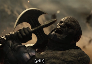 Darkseid taking an axe to the shoulder. The closed caption says "yells."