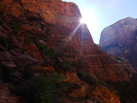 Rocky mountainside with lots of craggy texture with a sunlight beaming around the edge