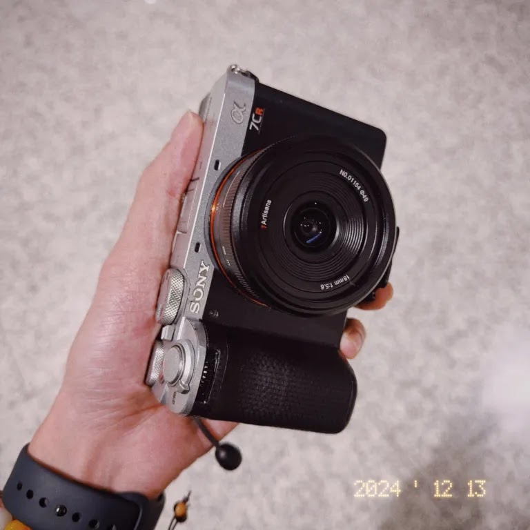 Объектив 7Artisans 18mm f/5.6 с камерой Sony в руке фотографа, вид спереди