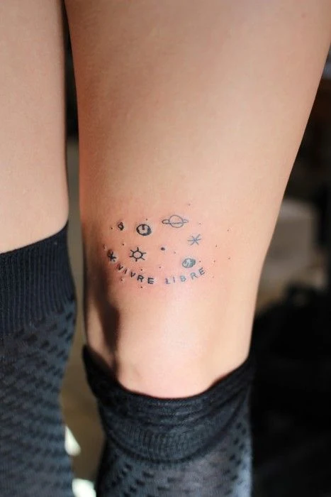 Pierna de una chica con calcetines, lleva en la rodilla tatuaje de planetas