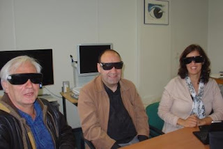 Fotografia de 3 Técnicos da Fundação Sain a experimentarem óculos com várias percentagens de bloqueio da luz 