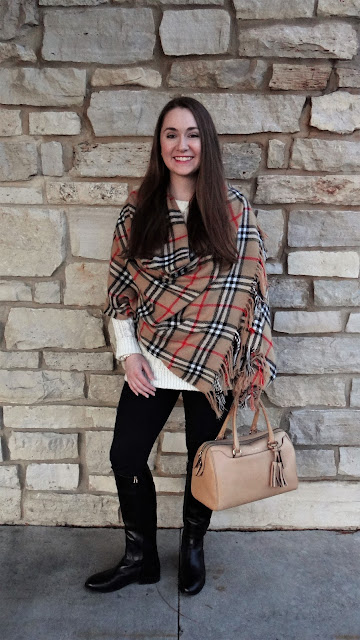 Model is wearing oversize white knit sweater with a Burberry plaid shawl and gold accessories.