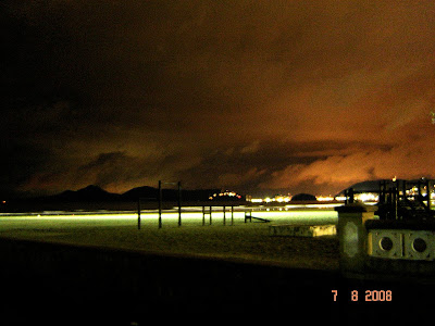 Foto noturna da praia de Santos tendo ao fundo a Ilha Porchat iluminada e a ilha Urubuqueçaba - Foto de EMILIO PECHINI em 07/08/2008