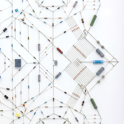 Technological Mandala, the work by Leonardo Ulian. A complex symetry pattern made from electronic components and microchips. It shows contrast between hard cold tech objects in a warm spiritual Hinduism symbol.