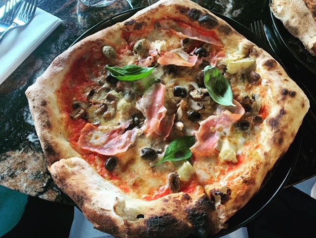 authentic capricciosa pizza, topped with artichokes, black olives, mushrooms and ham