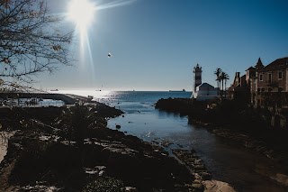 farol de santa marta ao fundo com o mar por baixo e pedras, que formam uma pequena enseada