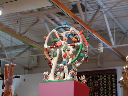 Photo of a child's toy. A white Ferris wheel with toys dangling from it where there would be gondolas for passengers.