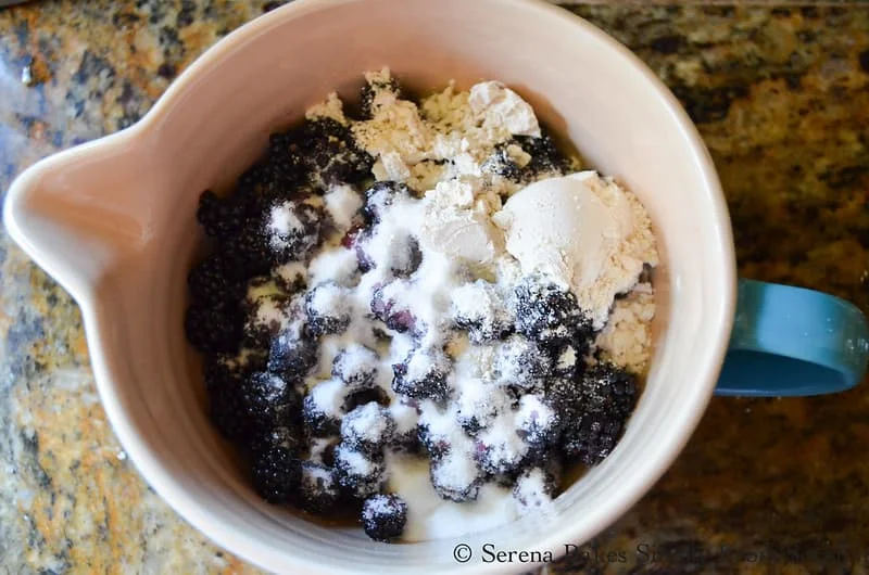 Blackberries in a bowl with granulated sugar and flour.