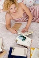 woman reading book lying on bed