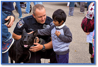 A police officer talking to a young boy who is petting a K-9.