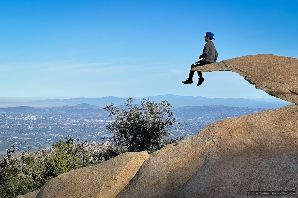 Person sitting on the edge of Potato Chip Rock, an arching sandstone fragment that remained when the rest of the rock collapsed.