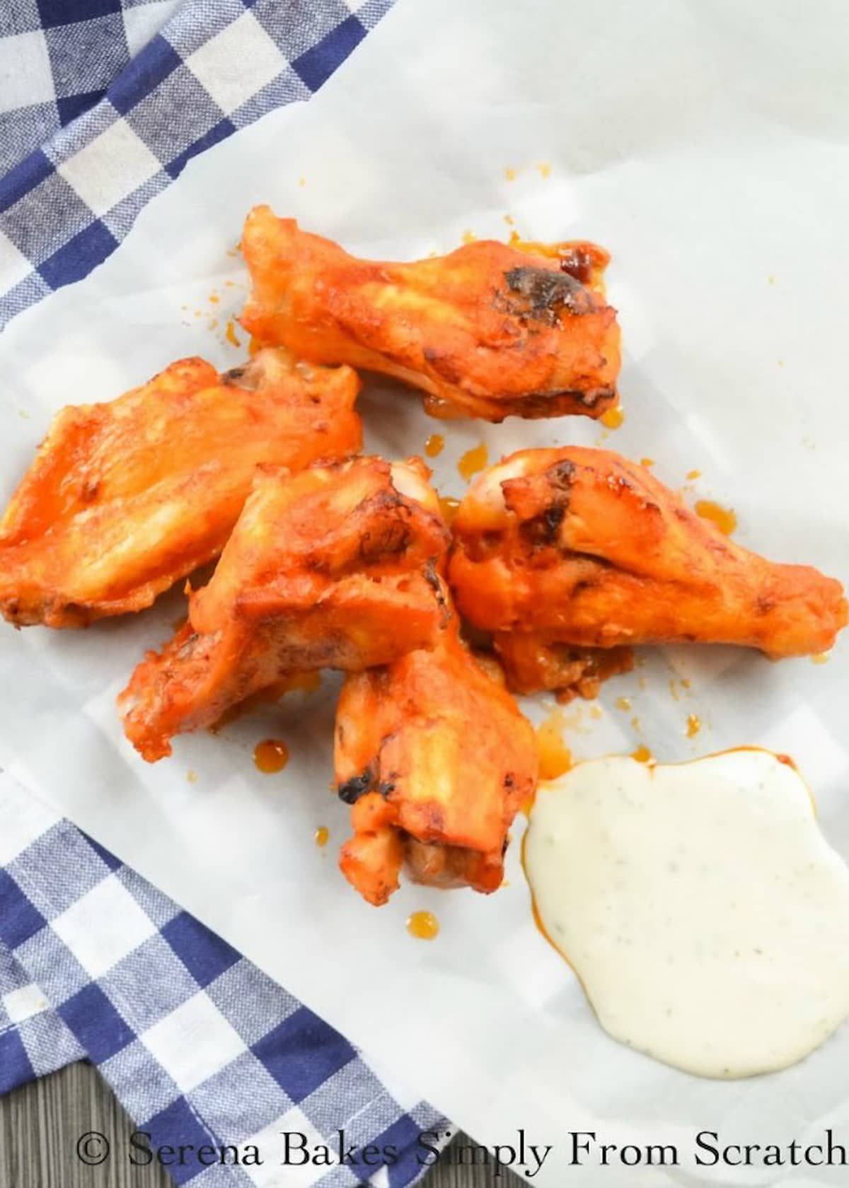 Baked Hot Wings on a white plate with a checkered blue napkin under the plate.