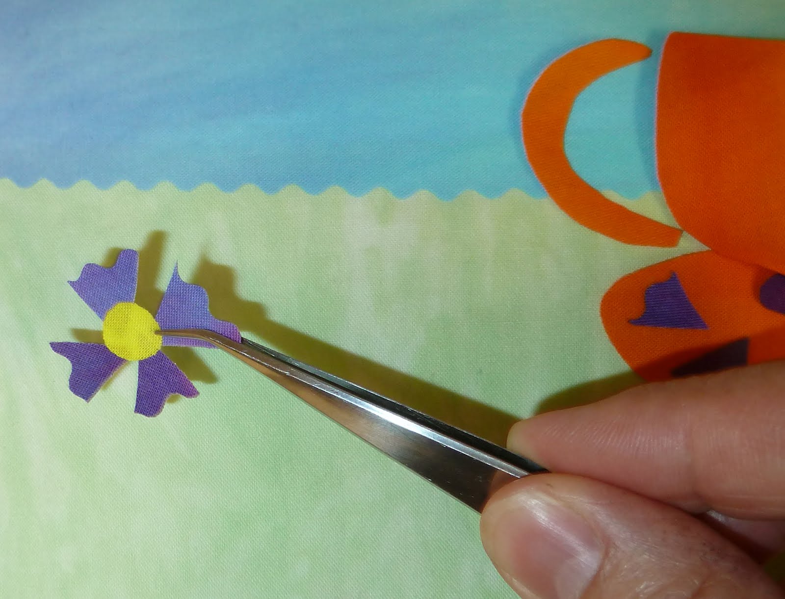 After the fabric cools, slide the tweezers under the flower unit and ...