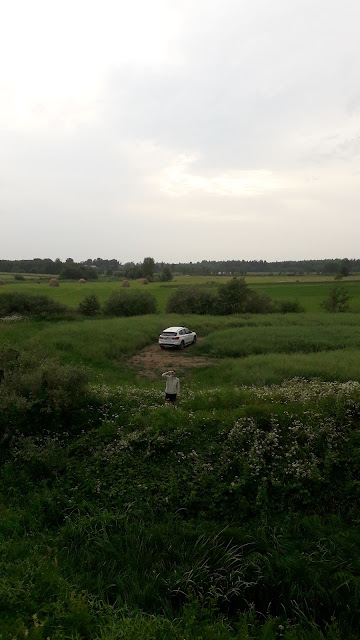 a young woman standing in a lush Latvian countryside from above