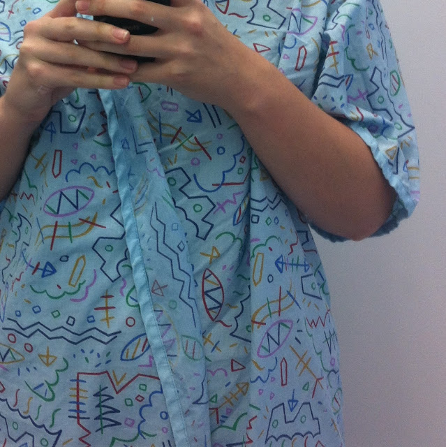 Photo of the hospital gown I was given to wear during my MRI. It is light blue with a colourful abstract line drawing design on it.