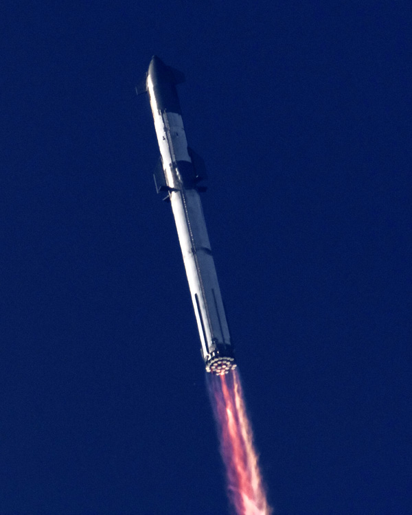 Starship Super Heavy ascends into the clear blue Texas sky after lifting off from Starbase on its maiden flight...on April 20, 2023.