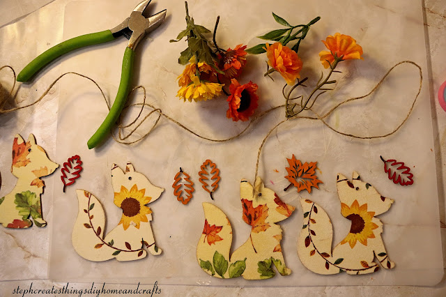 Wooden foxes with decoupage decorative napkin design, twine, floral cutters, wooden leaves, and faux floral on a table