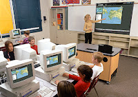 classroom of students sitting at computers with teacher at front using SMARTboard