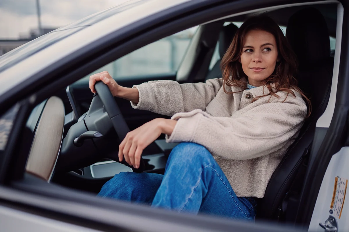 woman sitting inside of an electric car and posing for the camera