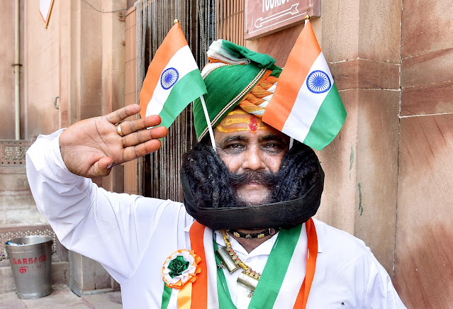 Girdhar Vyas, claiming have the longest moustaches in the world, poses with the National flags as part of the 75th Independence Day celebrations, in the western Indian city of Bikaner.