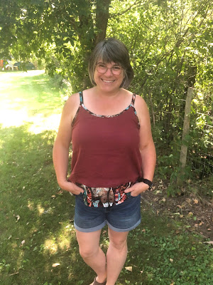 Sarah stands facing the camera in a colour blocked Orchard Top and denim jeans.