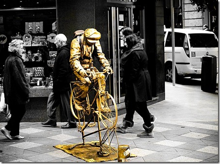 El ciclista dorado espera unas monedas para pedalear.