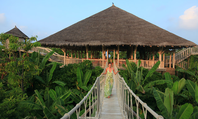 Photo of women in green dress coming out of one of the residences above the palm trees