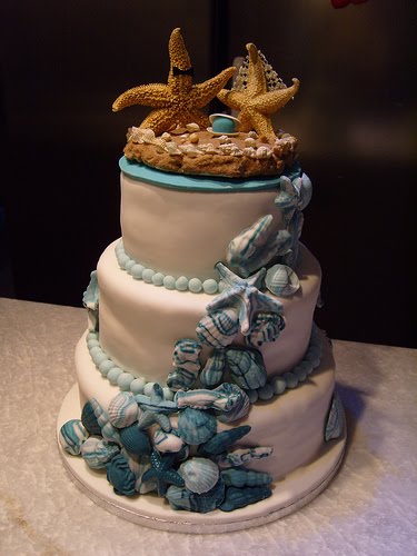 Elegant beach theme wedding cake encrusted with blue seashells and cute 
