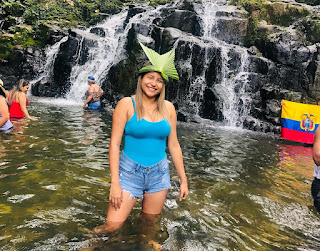 Chica sonriente con una bandera del Ecuador, disfrutando de la majestuosidad de la hermosa Cascada Yanayaku en Archidona Napo, en un momento de orgullo nacional y conexión con la naturaleza.