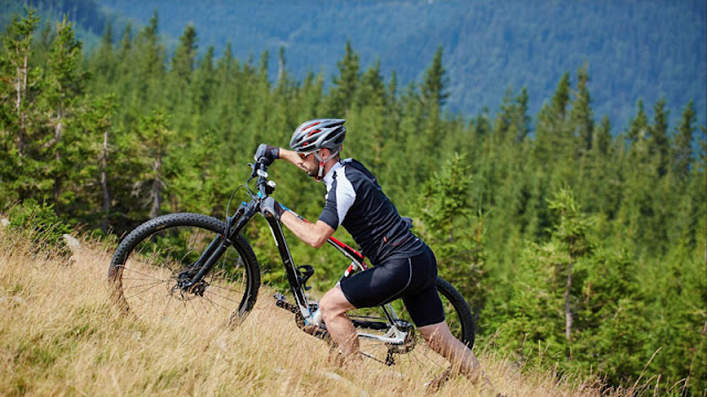 Biker walking bike up hillside