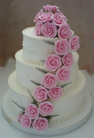 Classic three tier white wedding cake with light pink sugar roses cascading 