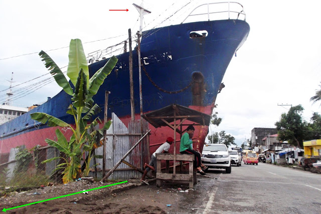 showing the sidewalk and bystanders with M/V Eva Jocelyn's bow just beside them