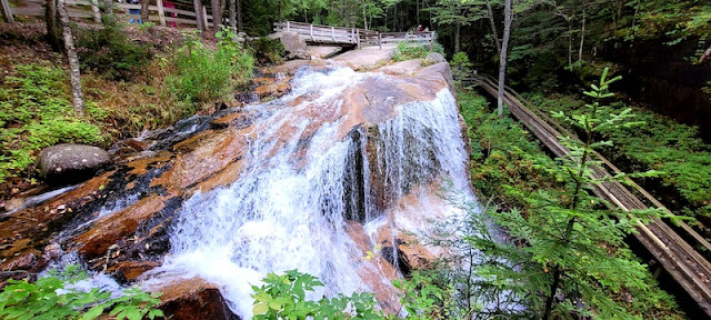 Water flowing over large boulders. Boardwalk trail going around the boulder.